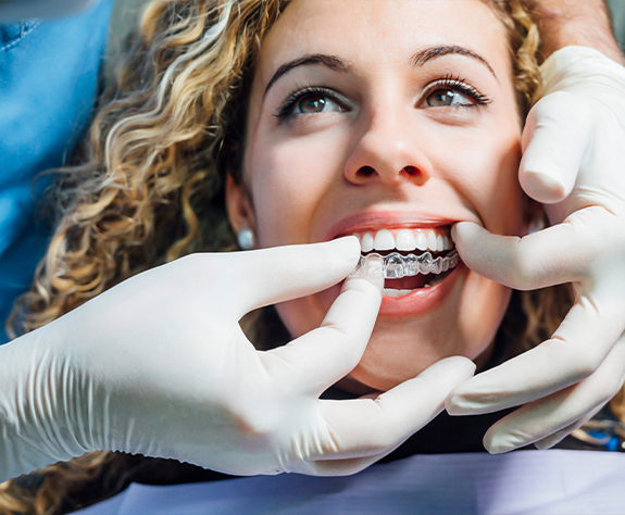 Dentist placing an Invisalign tray over dental patient's smile