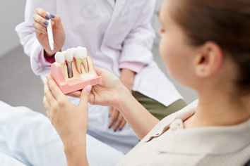 A dental patient holding an enlarged dental implant model