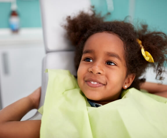 Child smiling during dental checkup and teeth cleaning with children's dentist