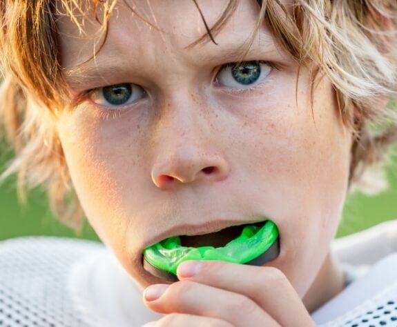 Teeh placing a green custom athletic mouthguard