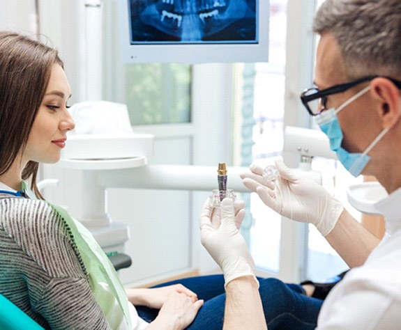 A dentist showing a dental implant to his patient