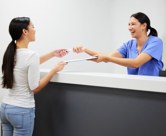 Smiling front desk team member and patient