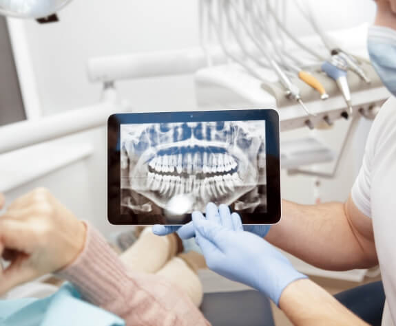 Dentist and dental patient looking at all digital x rays on tablet computer