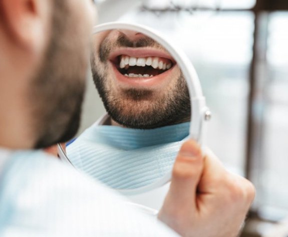 a patient checking his renewed smile in the mirror