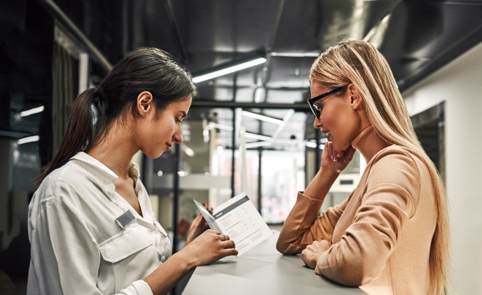 Dental team member talking to woman at front desk in dental office