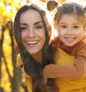 Smiling mother giving child piggyback ride outdoors