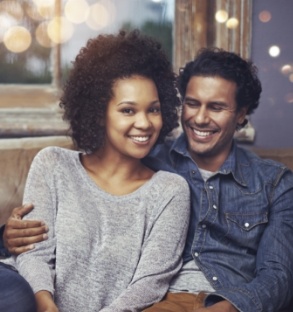 Smiling man and woman sitting on couch