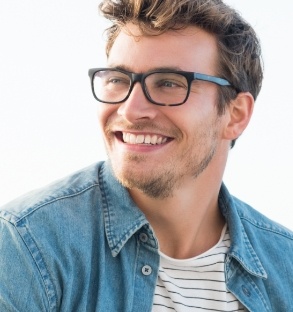 Young man with glasses and denim shirt grinning