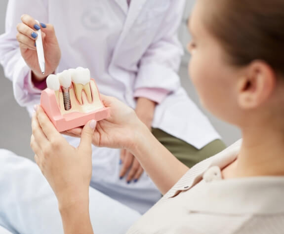 Dentist and dental patient looking at dental implant model