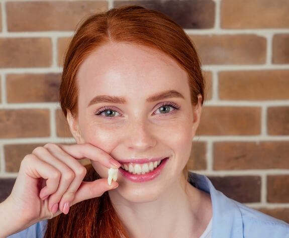 Young woman holding a wisdom tooth after extraction