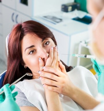 Woman in need of gum disease treatment covering her mouth