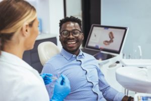 a man smiling while speaking with his dentist at his checkup