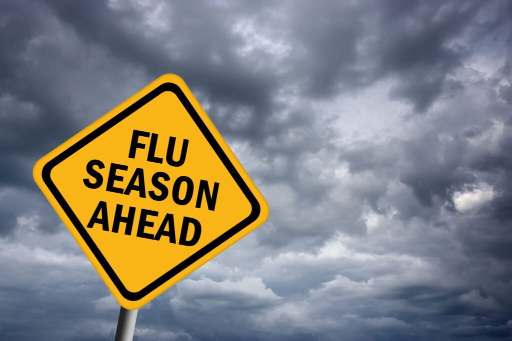 Caution "Flu Season Ahead" sign in front of cloudy skies