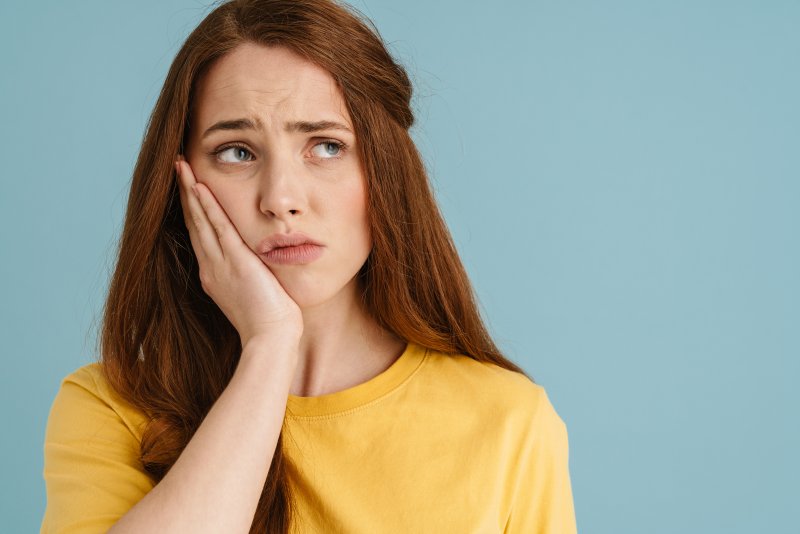 A young woman looking aside while suffering a toothache